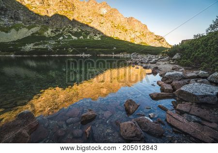 Mountain Lake Rocks in Foreground at Sunset. Velicka Valley High Tatra Slovakia.