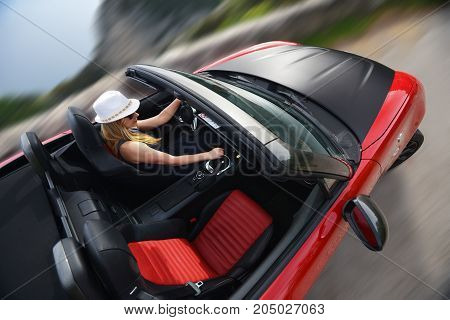 Woman and red cabriolet on winding mountain road