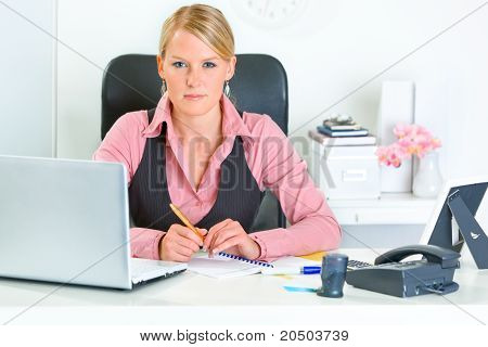 Mujer de negocios moderno autorizada sentado en el escritorio de oficina
