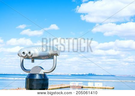 Stationary binoculars for tourists. Sea. Beautiful clouds background. Look into the distance.