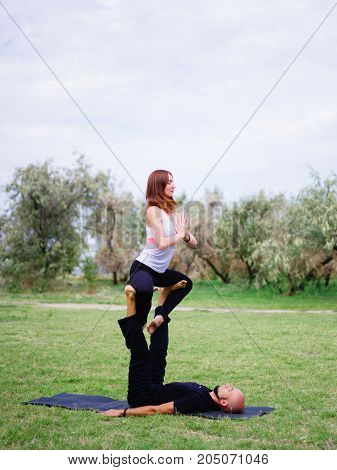 Beautiful woman and girl practise yoga pose outside. Women doing stretching workout in park outdoors at sunset.