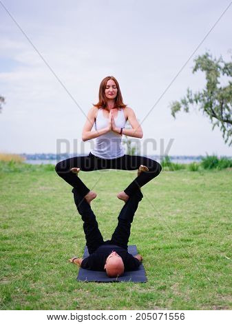Beautiful woman and girl practise yoga pose outside. Women doing stretching workout in park outdoors at sunset.