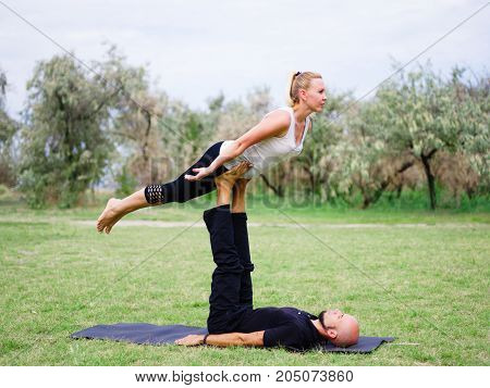 Beautiful woman and girl practise yoga pose outside. Women doing stretching workout in park outdoors at sunset.