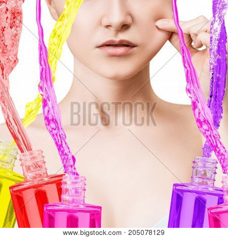 Young woman's face and among oil bottles with splashes. Beauty therapy concept.