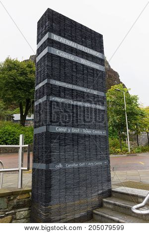 Street sign giving directions made out of slate in the historic Welsh mining town of Blaenau Ffestiniog in English and Welsh languages