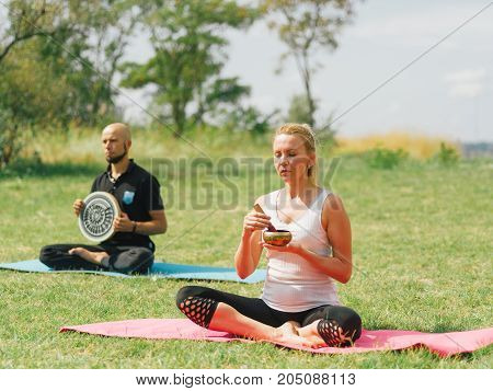 People at the health club outside with personal trainer, learning the correct form.