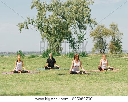 People at the health club outside with personal trainer, learning the correct form.