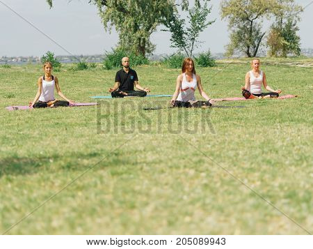 People at the health club outside with personal trainer, learning the correct form.