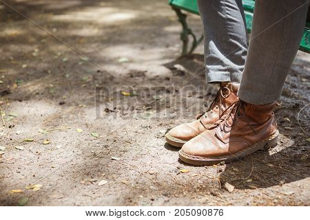 Young fashion hipster man's legs in brown leather boots and wearing gray jeans with both feet stepped on the floor ground concept of fashion and vintage lifestyle.