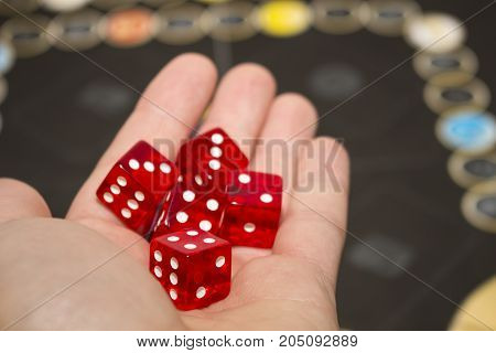 Several rolling red dice fall on a table with boardgame. Gameplay moments.