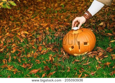 Closeup On Woman Putting Candle In Pumpkin Jack O’lantern