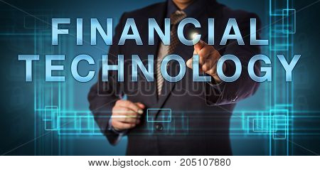 Unrecognizable corporate manager is pointing at FINANCIAL TECHNOLOGY on a touch screen. Business and IT concept for FinTech and financial services provided as end to end process via the internet.