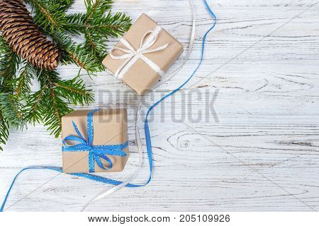 Christmas gift box on the white wooden table backgroundspruce branchpine conesframetop viewspace for text.