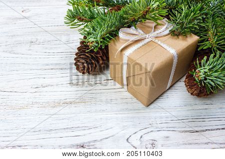 Christmas gift box on the white wooden table background spruce branch pine cones frame top view space for text.