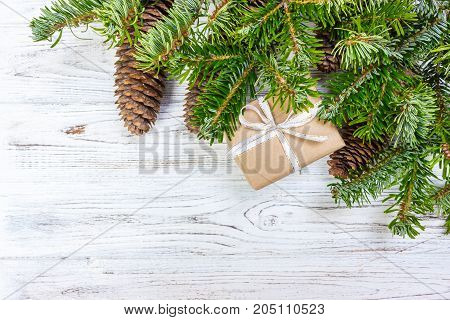 Christmas gift box on the white wooden table background spruce with branch pine cones frame top view space for text.