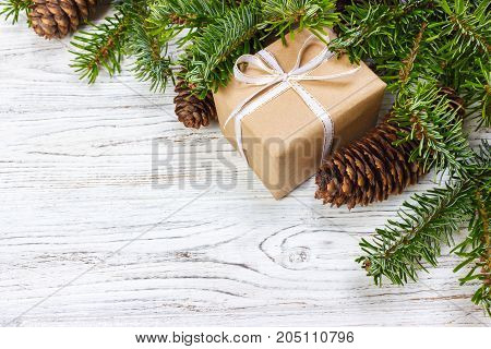 Christmas gift box on the white wooden table backgroundspruce branchpine conesframetop view space for text.