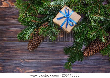Christmas gift box on the wooden table backgroundspruce branchpine conesframetop view space for text.