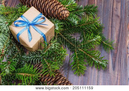 Christmas gift box on the wooden table backgroundspruce branchpine conesframetop view space for text.