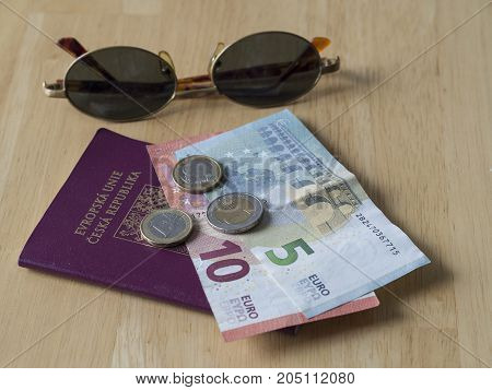 travel south europe - five and ten euros bank bill and two and one euro coins on EU passport czech republic and sun glasses - tropical holiday