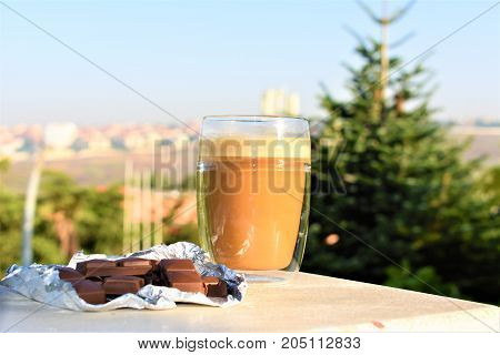 glass on the roof of the house. cappuccino on the roof. transparent mud with coffee. breakfast on the roof. view of the forest and the city. sunny day. beautiful background
