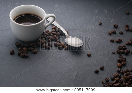 Coffee cup with a spoon and some coffee beans