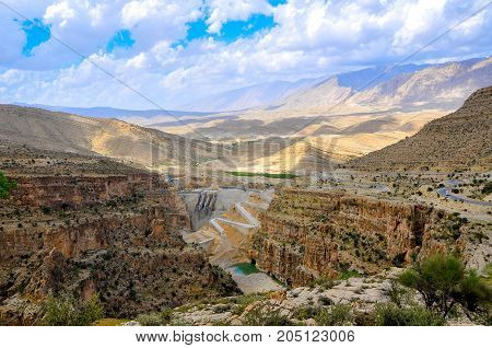 road in the hilly terrain of Iran runs along a big kanyen the dam nearby settles down
