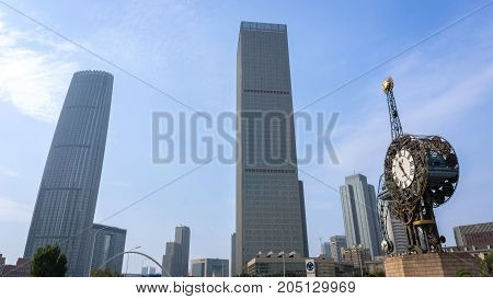 Tianjin, China - Nov 1, 2016: The Century Clock on a public park, along the Haihe River, against a backdrop of commercial buildings with modern architectural styling.
