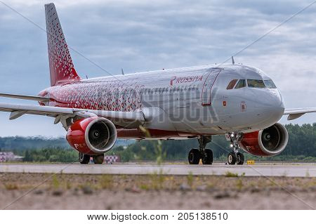Pulkovo, Saint-Petersburg, Russia - August 10, 2017:   The airplane Airbus A320 of Rossiya Airlines is taxi on the runway against the background of the forest and blue sky. Summer sunny weather