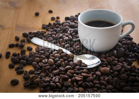 Coffee cup with spoon and some coffee beans