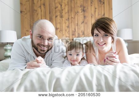 A Family with child. Happy parents playing with baby on bed