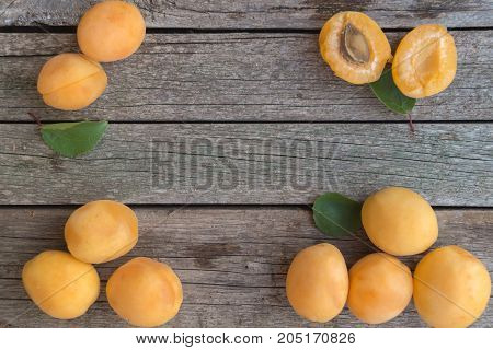 Ripe orange apricots are arranged on the left and right of grey wooden background