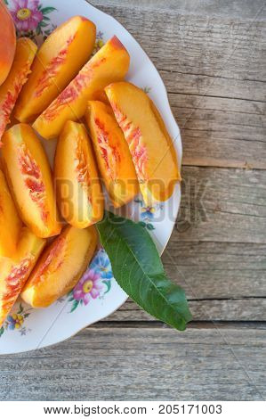 Slices of peach on the plate with knife on the tree stump