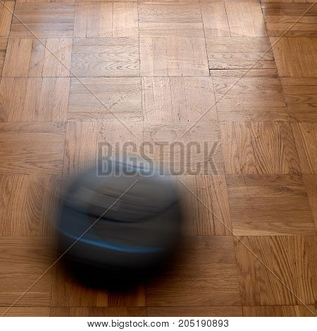 Robotic vacuum cleaner cleaning dust on laminate floor, natural movement, natural motion blur. image with square aspect ratio
