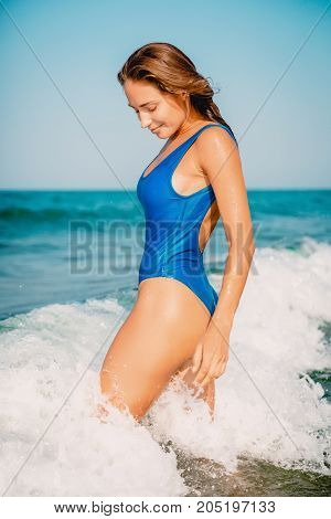 Beautiful woman go to swim in ocean. Crystal blue sea and wave on tropical beach. Vacation in paradise. Ocean beach relax in Bali