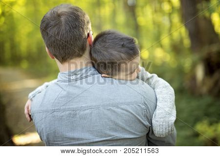 A Little boy and his father on grass in autumn forest