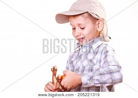 Nature and free time prankster little boy. Child have fun with wooden sling shot and fruit hold mandarine.