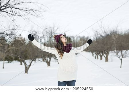 A Young happy pregnant woman in snowy forest