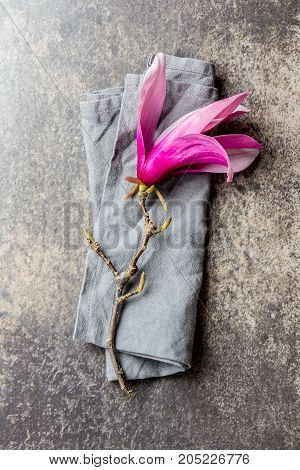Purple flower of magnolia on stone background. Top view.