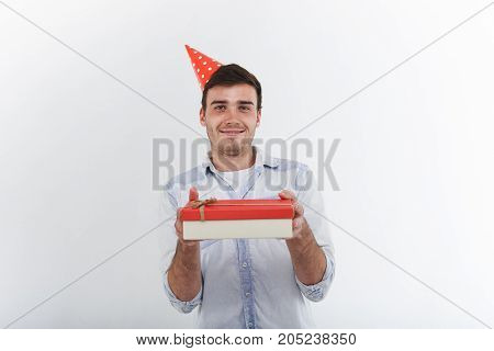 Joy happiness celebration partying anniversary and special occasions concept. Attractive cheerful young man in blue denim shirt holding big box of present reaching out hands at camera and smiling