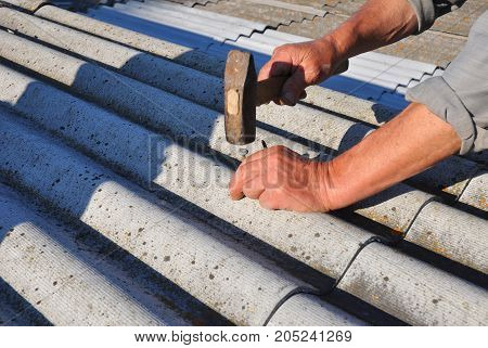 Asbestos Removal. House asbestos roof repair with roofer hands. Roofers Roofing Construction and Roof Repair.