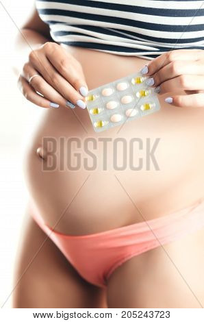 Pregnant Girl In The Hands Holding Pills