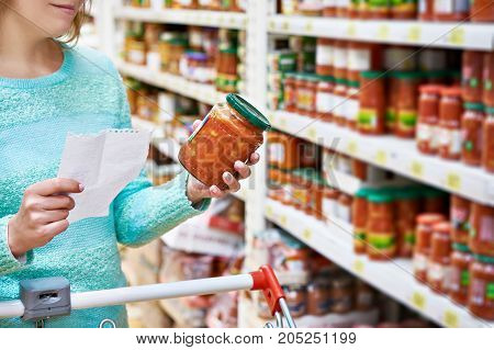 Woman chooses lecho tomato at the grocery store