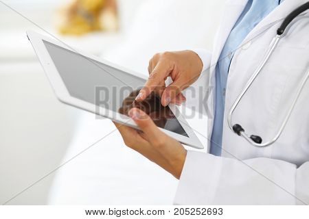 Woman doctor using tablet computer while standing straight in hospital.