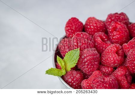 Close-up of fresh raspberriers with a mint leaf light background