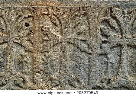 Sacred armenian cross stones khachkars ingraved on the wall of ancient monastery Geghard