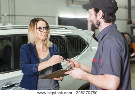 An auto mechanic and female customer in garage