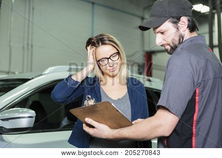 An auto mechanic and female customer in garage