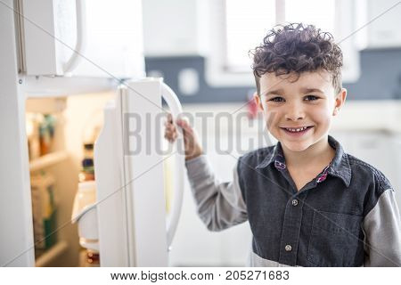 A Young white boy standing in front of open refrigerator.
