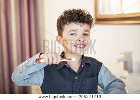 A kid boy brushing teeth on the bathroom