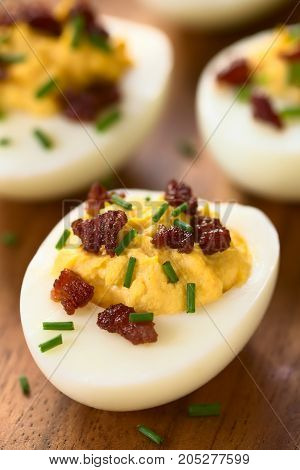 Deviled egg with bacon and chives photographed with natural light (Selective Focus Focus on the front of the egg yolk of the first egg)